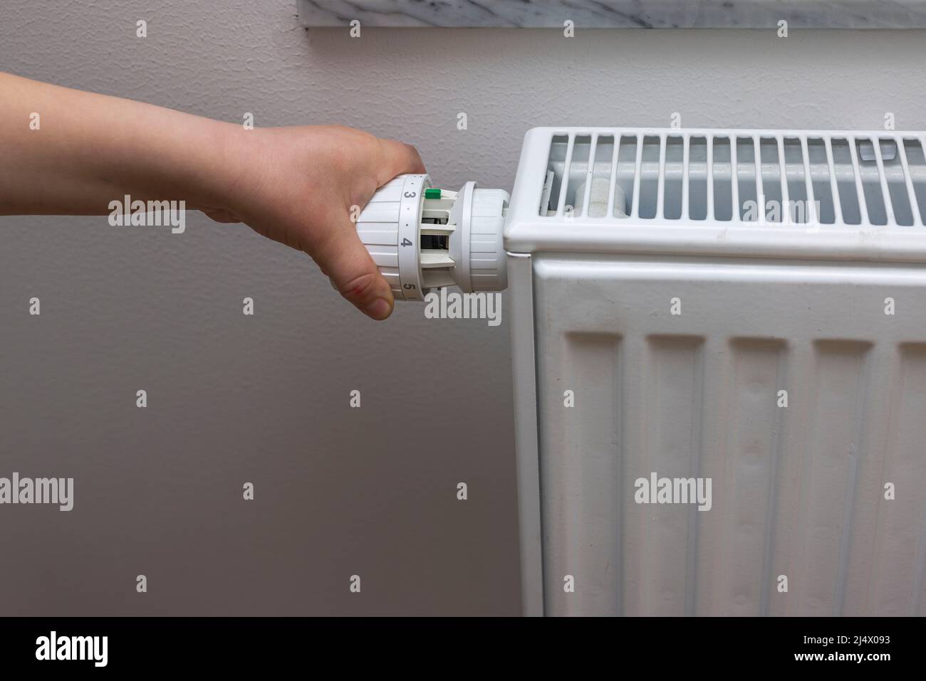 Close up view of child's hand turning off thermostat on heating radiator to save energy. Sweden