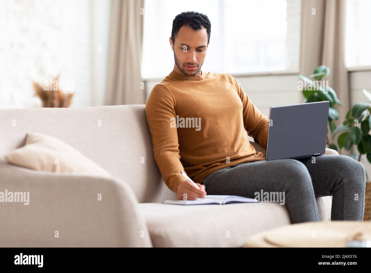 Portrait of focused Arab man using laptop and writing Stock Photo