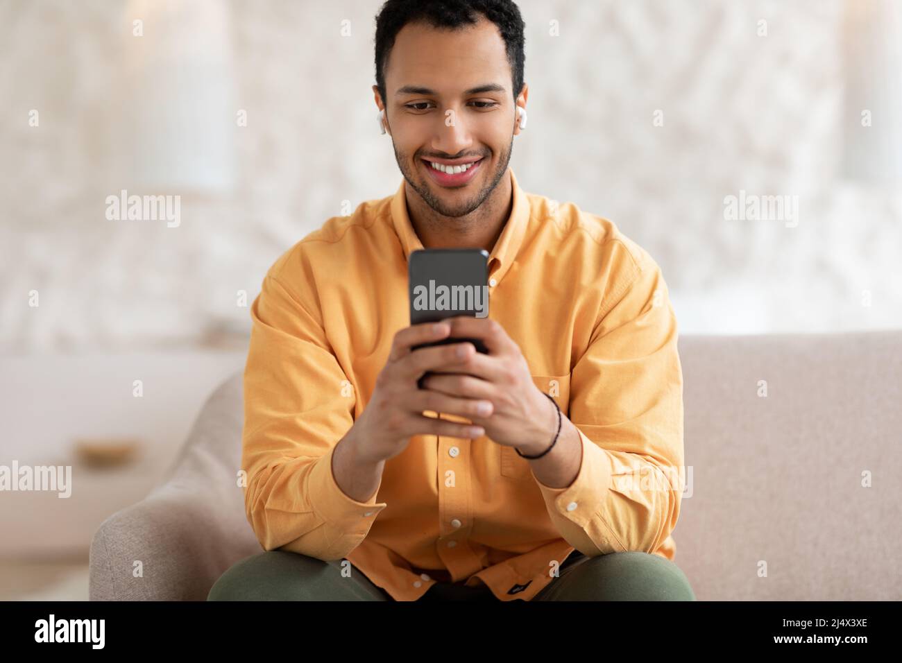 Happy Arab man using cellphone wearing headphones Stock Photo