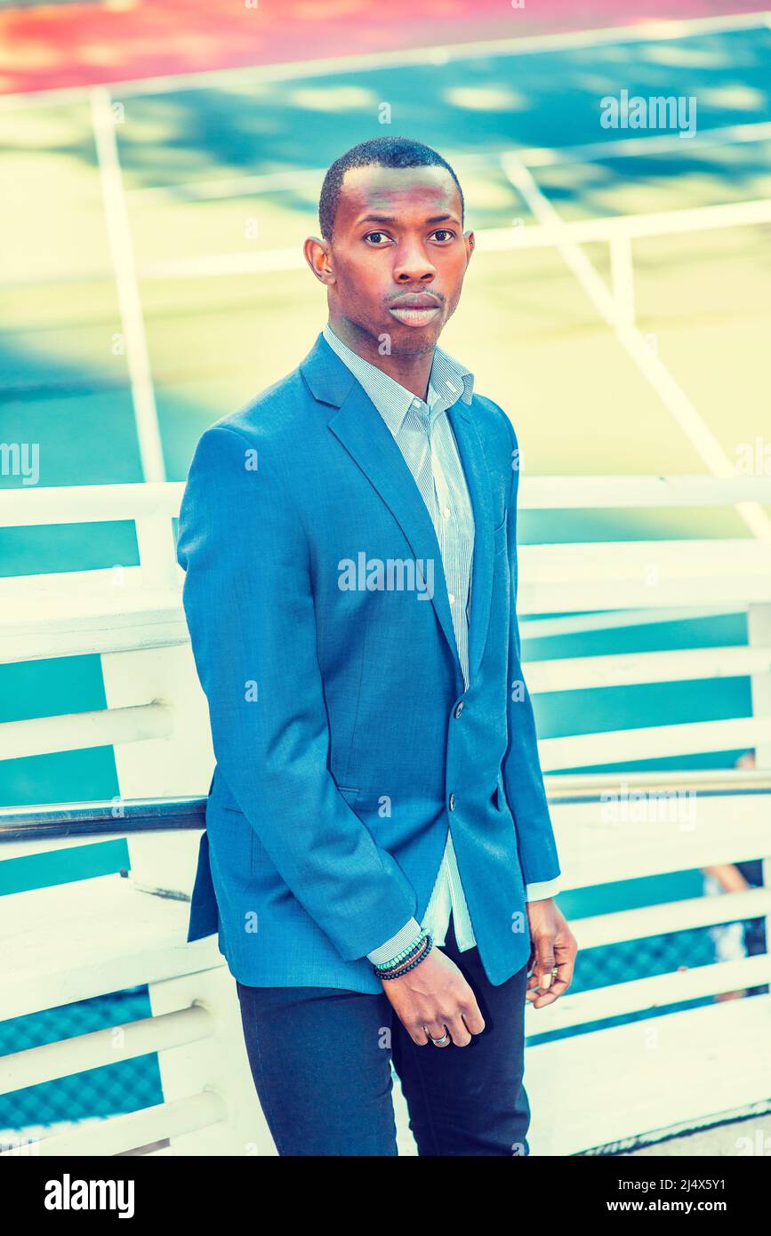 https://c8.alamy.com/comp/2J4X5Y1/man-waiting-for-you-wearing-a-blue-blazer-black-pants-short-haircut-a-young-black-guy-is-standing-against-metal-fences-by-a-tennis-court-staring-2J4X5Y1.jpg