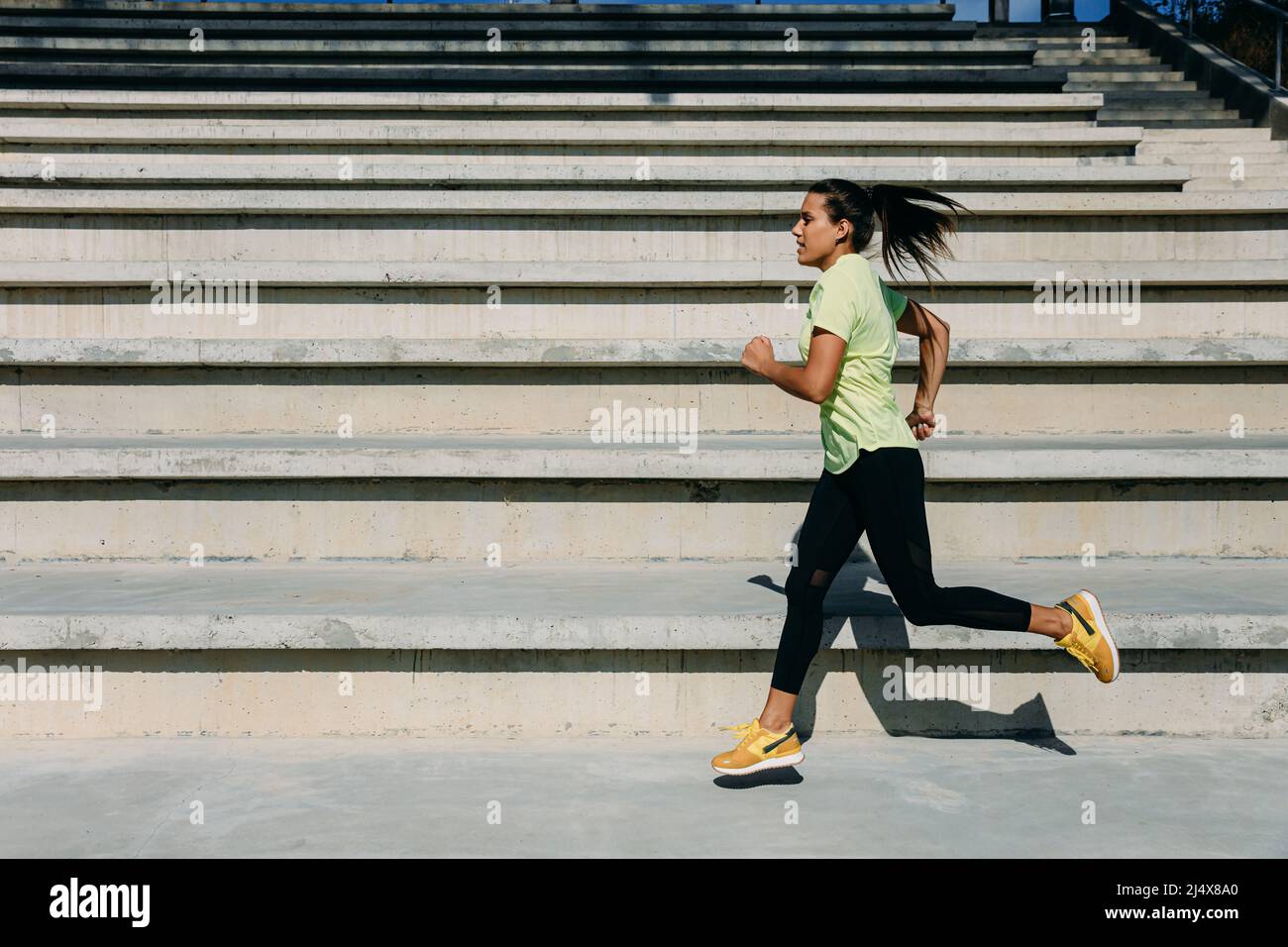 Focused female athlete jumping and running outdoors Stock Photo