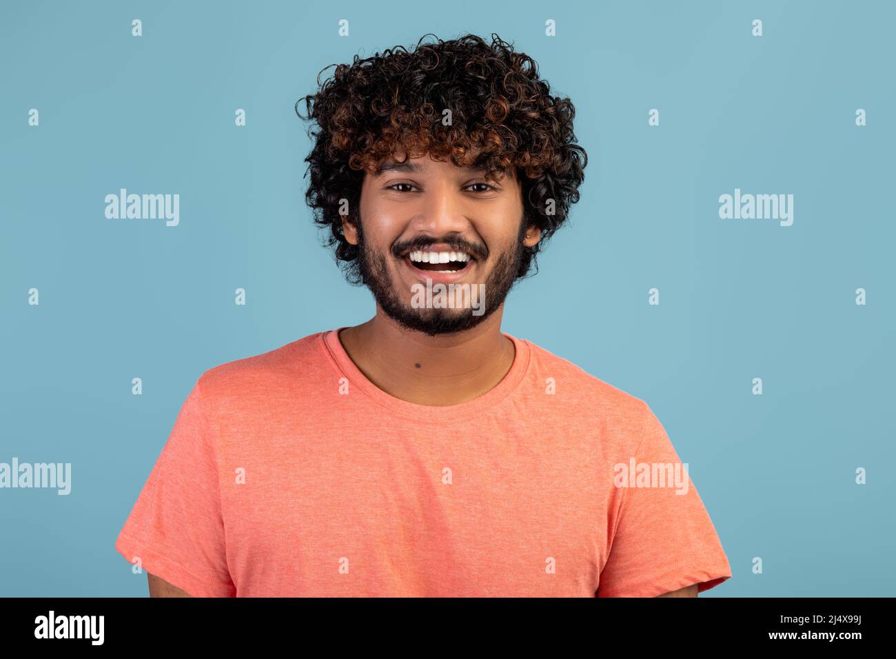 Portrait of positive handsome indian young man on blue Stock Photo