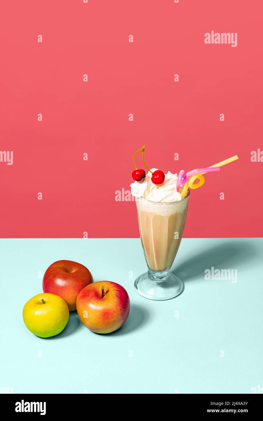 Irish coffee and apples. High glass with milk cocktail isolated on light pink background. Trendy colors. Pop art, retro style. Stock Photo