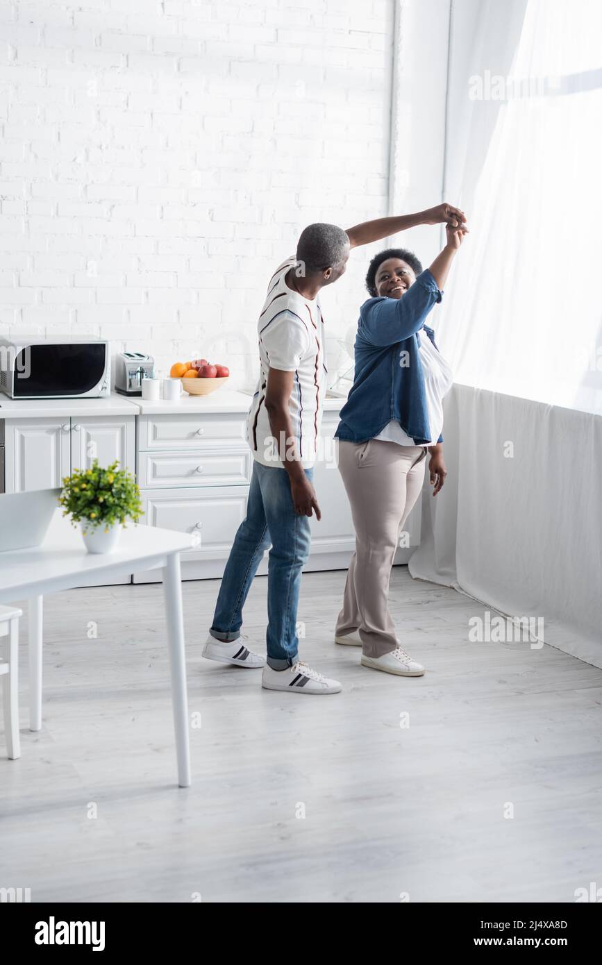 full length of happy senior african american couple dancing in kitchen ...