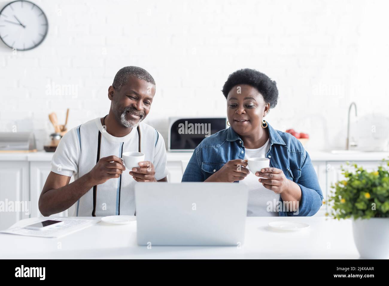 senior african american husband and wife holding cups and watching ...