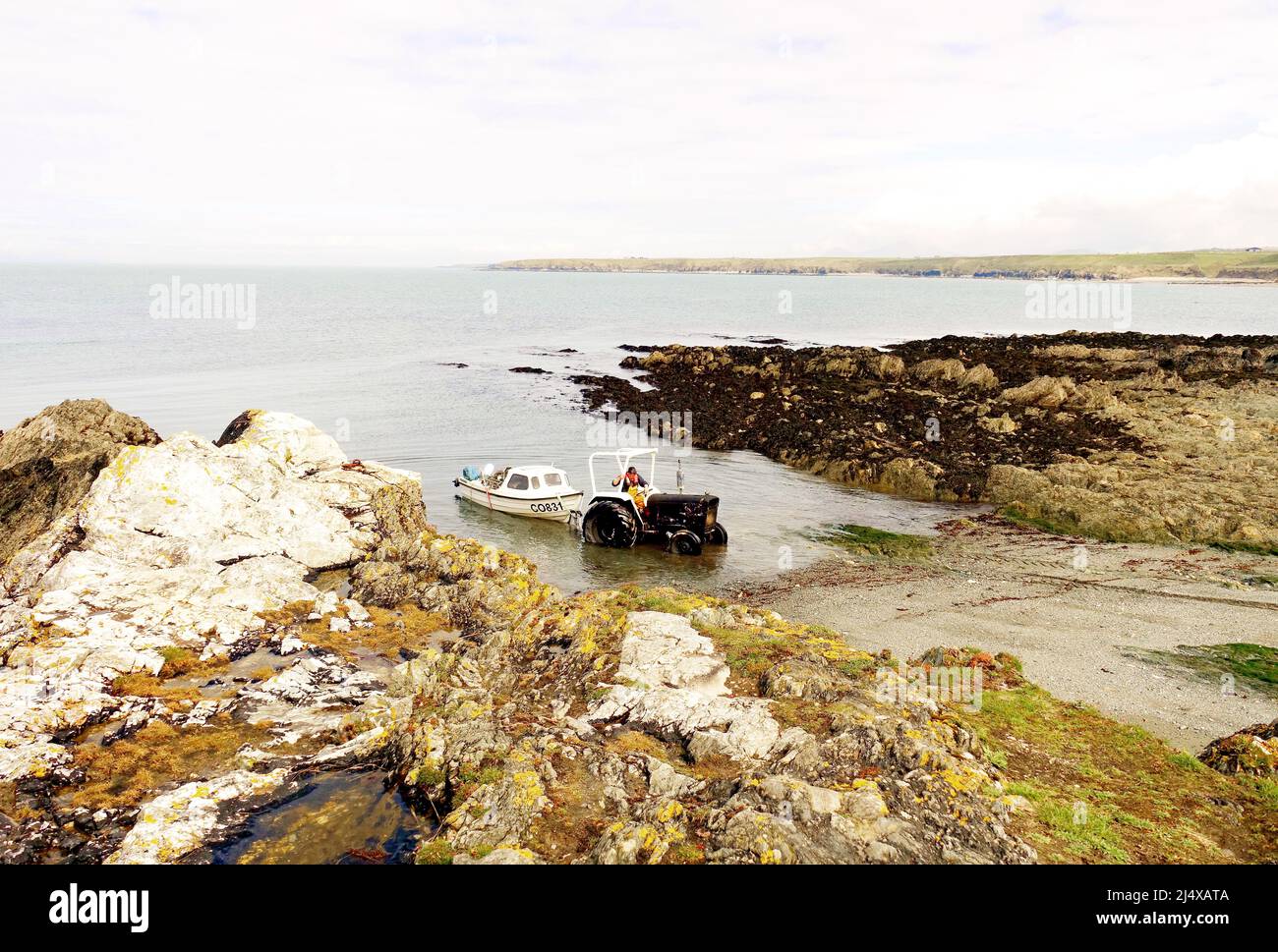 Welsh fisherman launches his boat into the tiny cove at Porth Conlon, on the beautiful Llyn Peninsula, Gwyneth, North Wales Stock Photo