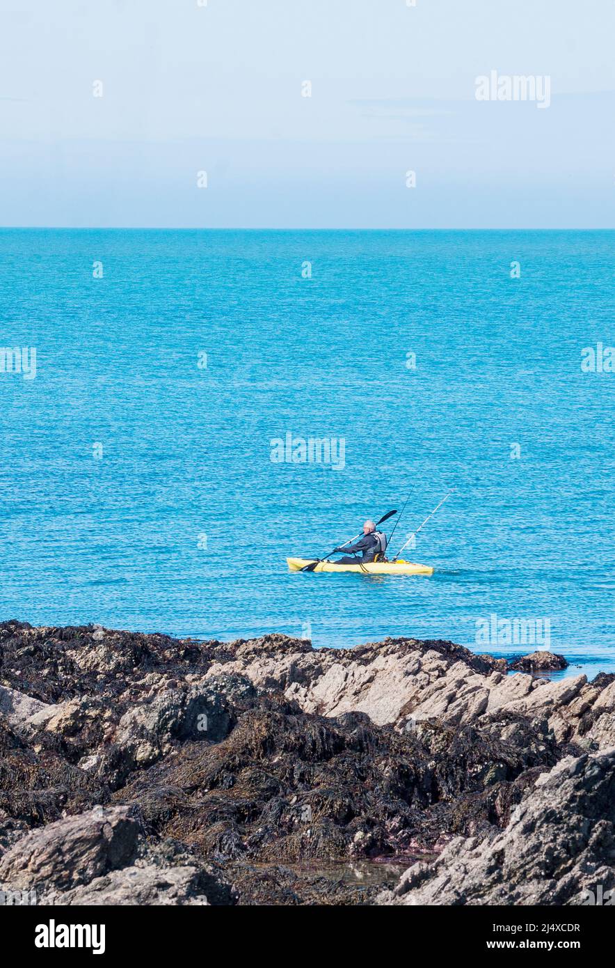 Sea kayaker sets out to do some fishing from the tiny cove at Porth Colmon, on the Llyn Peninsula,Gwyneth, North Wales Stock Photo