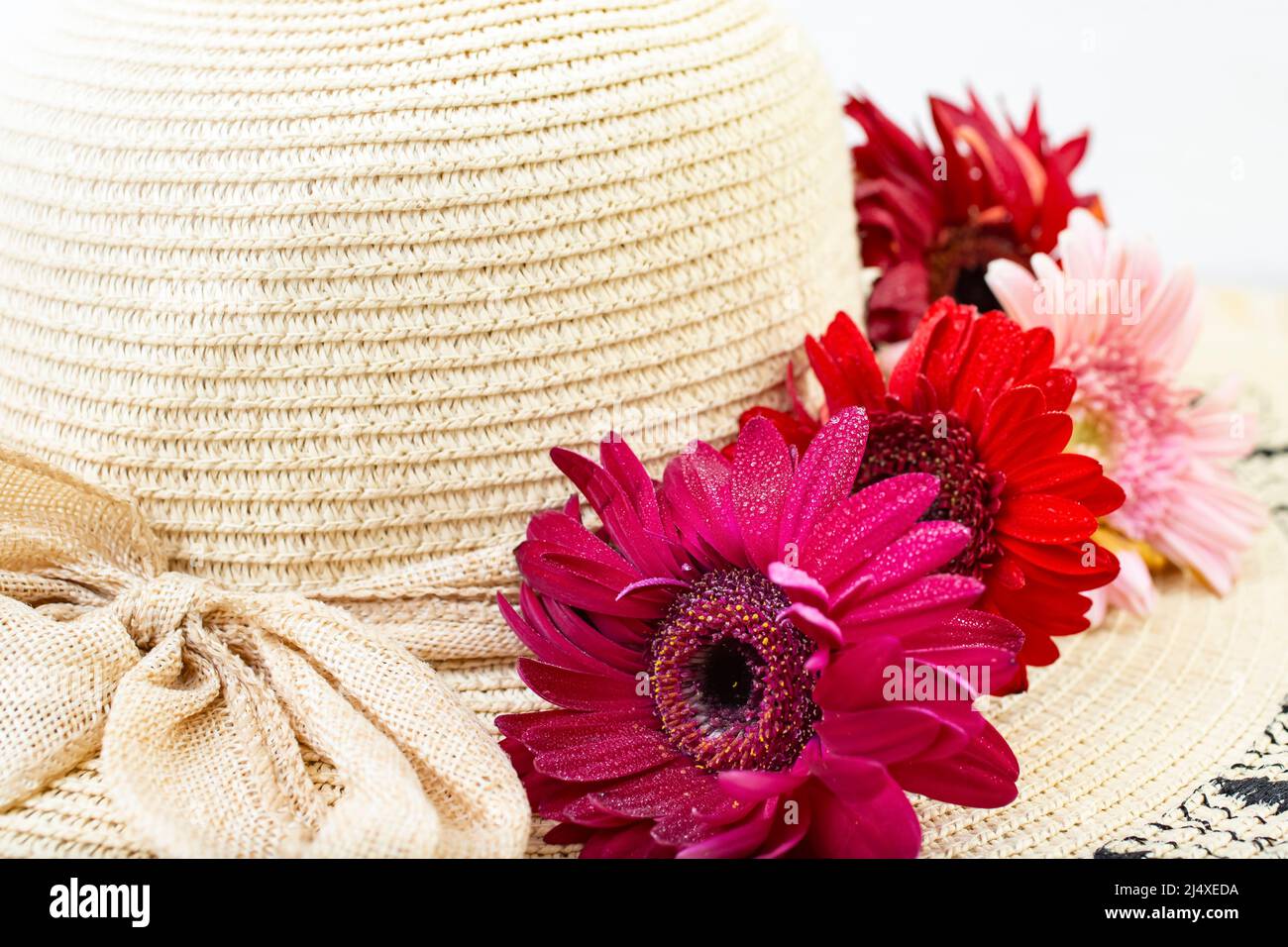 woman's sun hat with red daisies and jute bow on white background Stock Photo