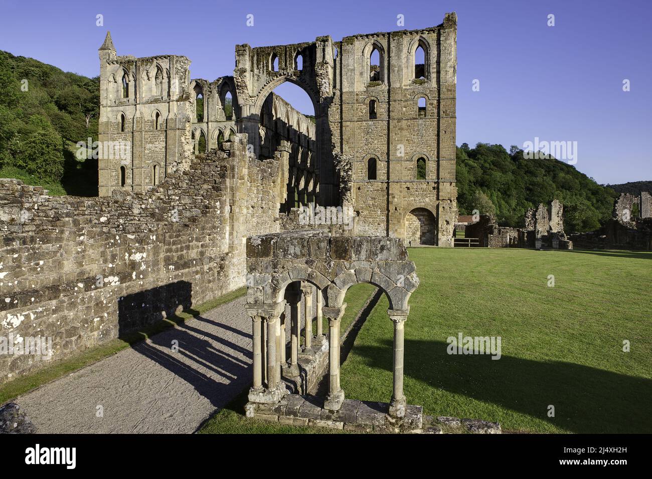 The reconstructed arcade (foreground) in the cloister with the presbytery behind showing north & south transepts of ruined Rievaulx Cistercian Abbey Stock Photo