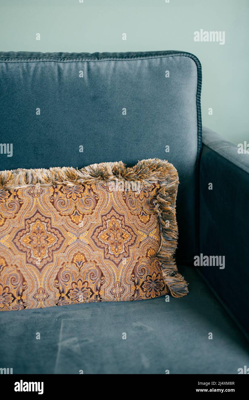 fringed pillow on a blue upholstered sofa Stock Photo