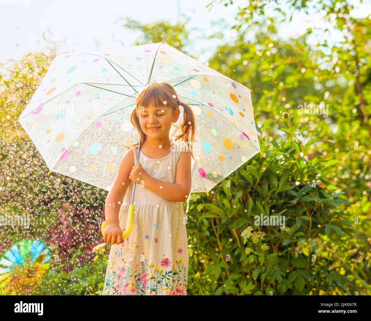 Happy little girl with an umbrella under the summer rain Stock Photo