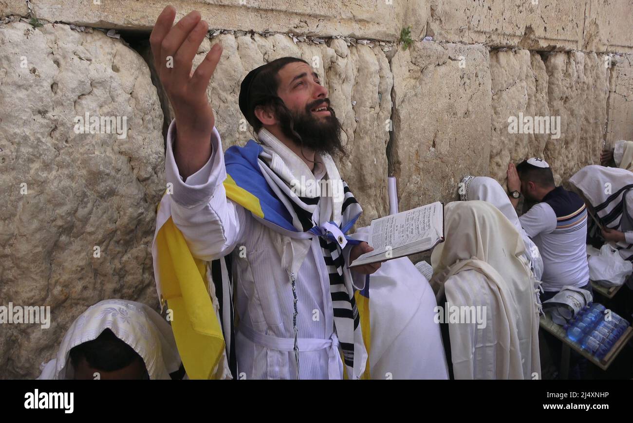A Jewish worshiper wrapped with the Ukrainian flag and Talit prayer shawl prays as religious Jews of the Cohanim Priestly caste take part in the bi-annual mass "Birkat Kohanim" or "Priestly Blessing" on the holiday of Pesach (Passover) at the Kotel in Jerusalem, Israel. Stock Photo