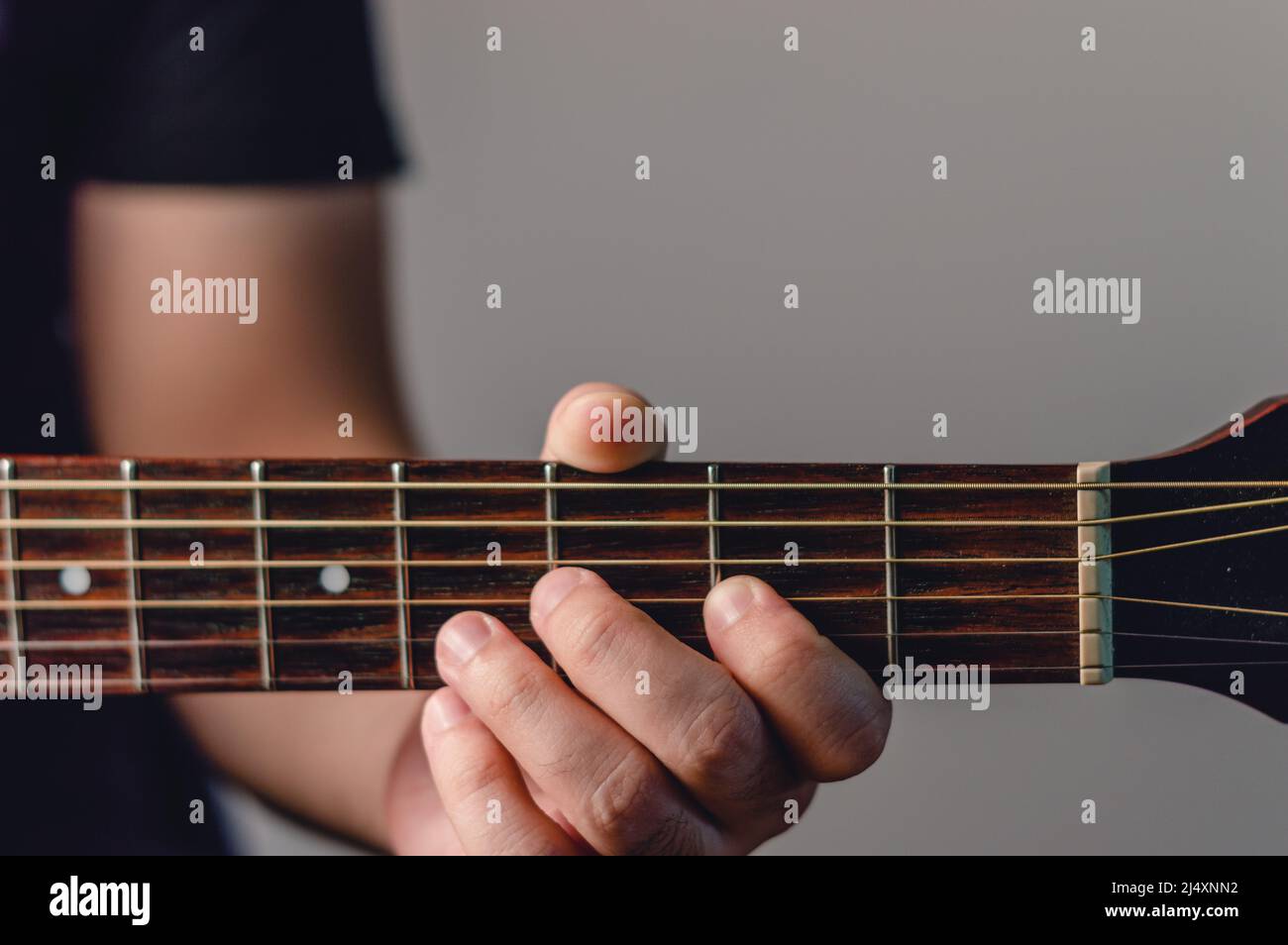 closeup and front view detail of male hand on acoustic guitar neck