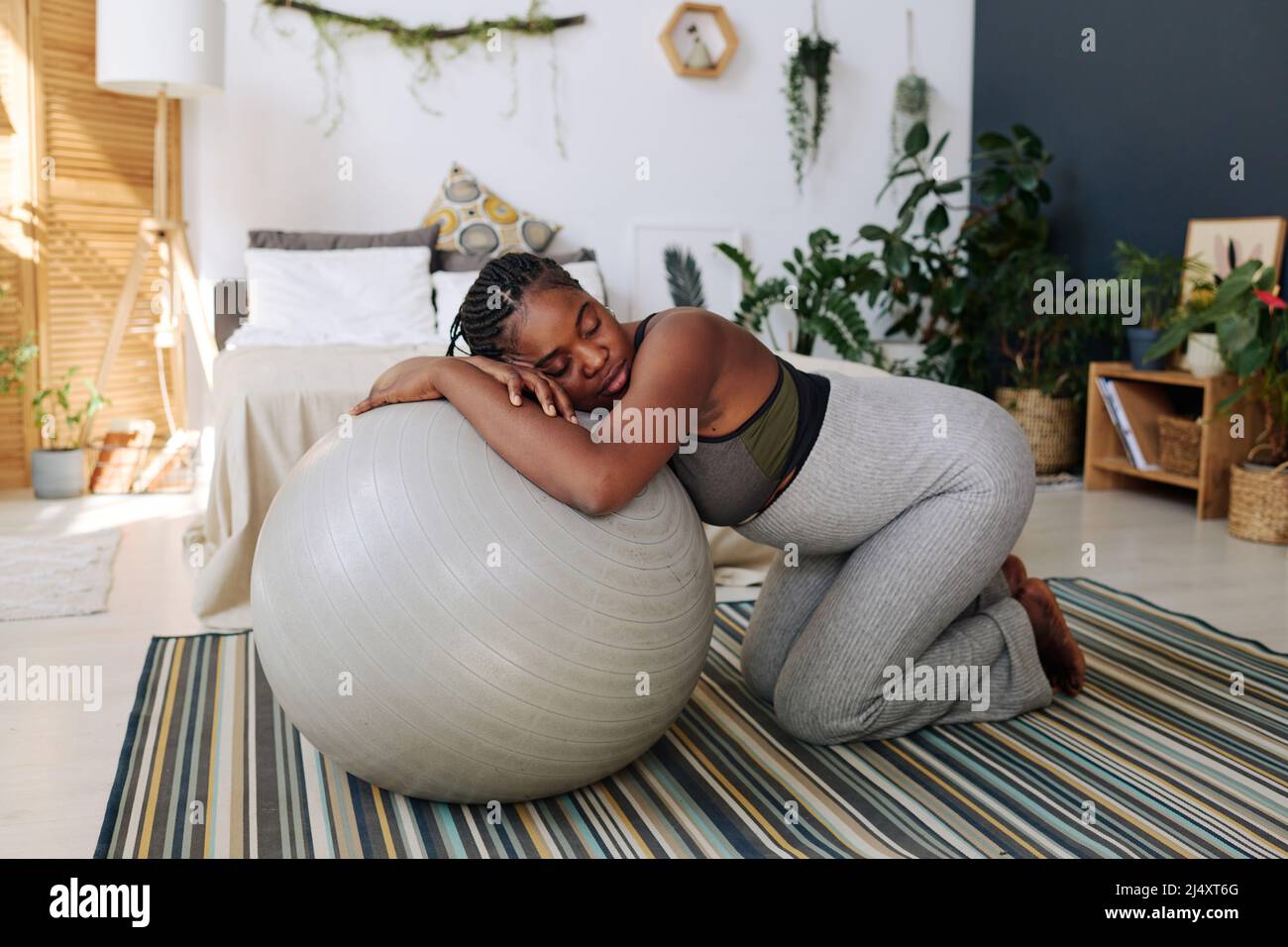 Young pregnant woman leaning on fitness ball during contractions suffering from pain Stock Photo