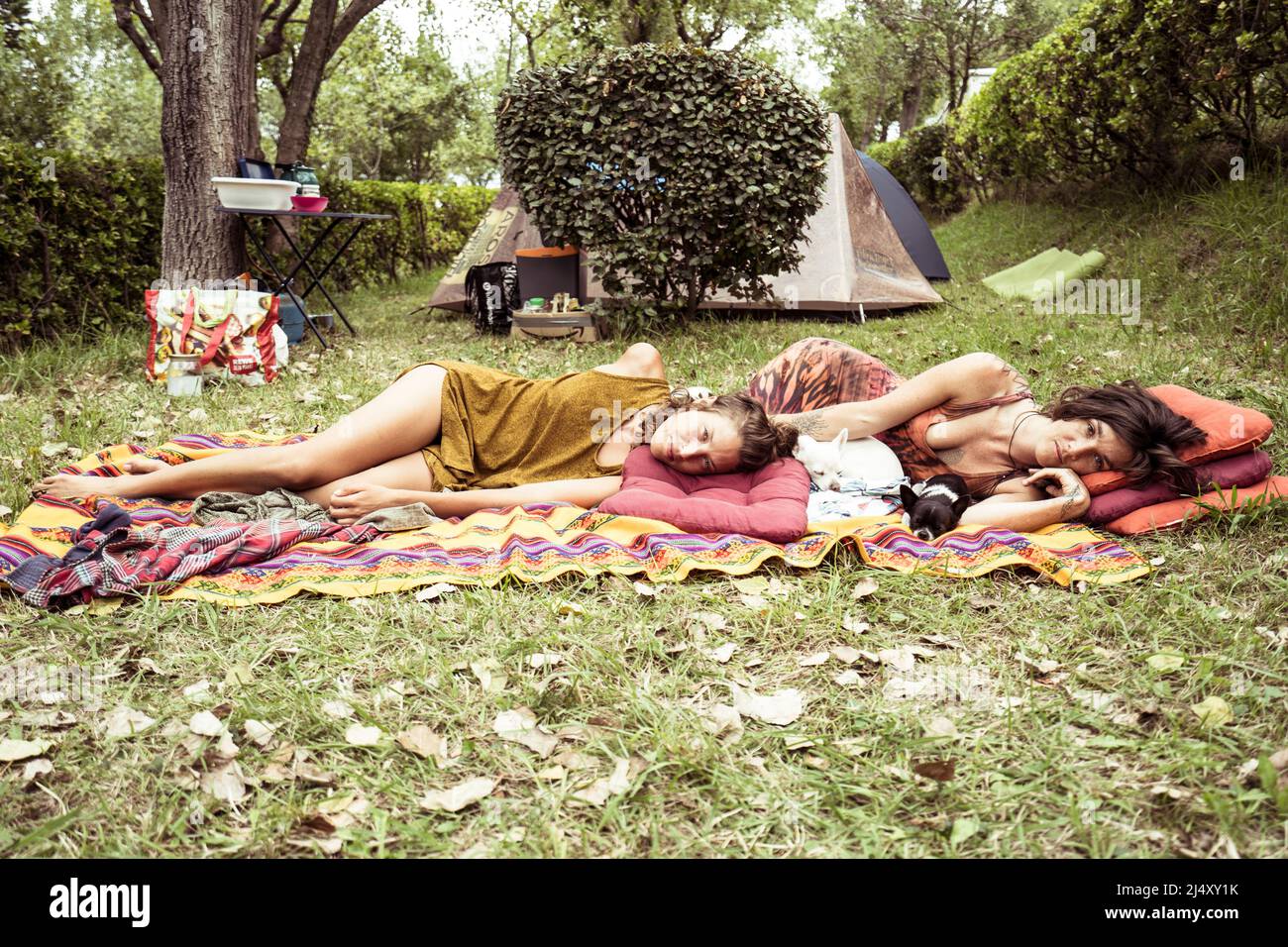 Two women relax together on grass in campsite in France Stock Photo