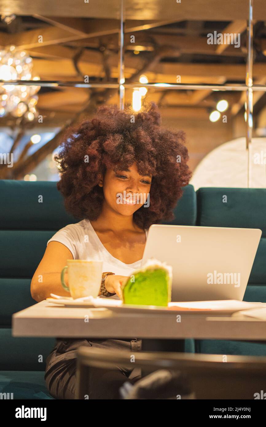 Young Afro woman in a coffee shop working online at her computer Stock ...