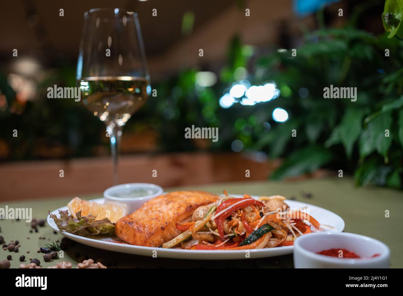 roasted salmon steak with wok vegetable and sauce on white plate in restaurant Stock Photo