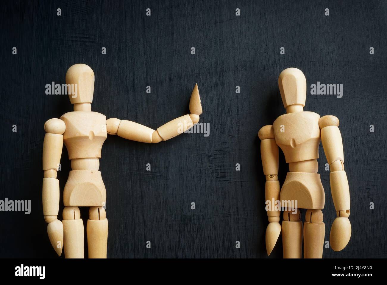 Assertiveness and confidence concept. Two wooden figurines on the dark surface. Stock Photo