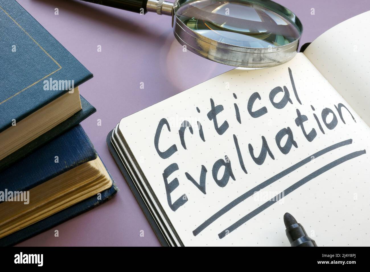 Open notebook with critical evaluation sign and magnifying glass. Stock Photo