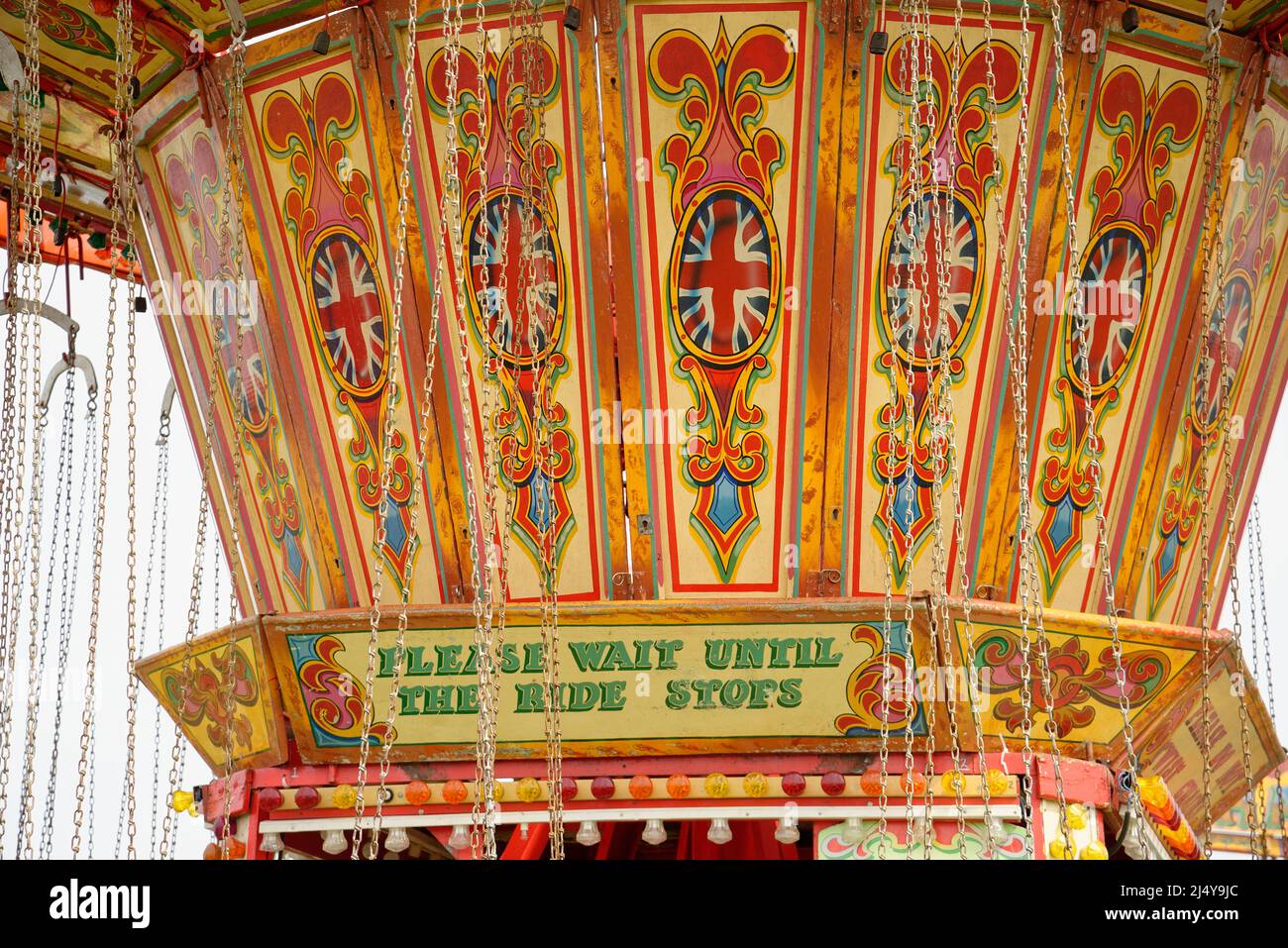 'Please Wait Until The Ride Stops' sign on a fairground swinging chairs ride. Stock Photo