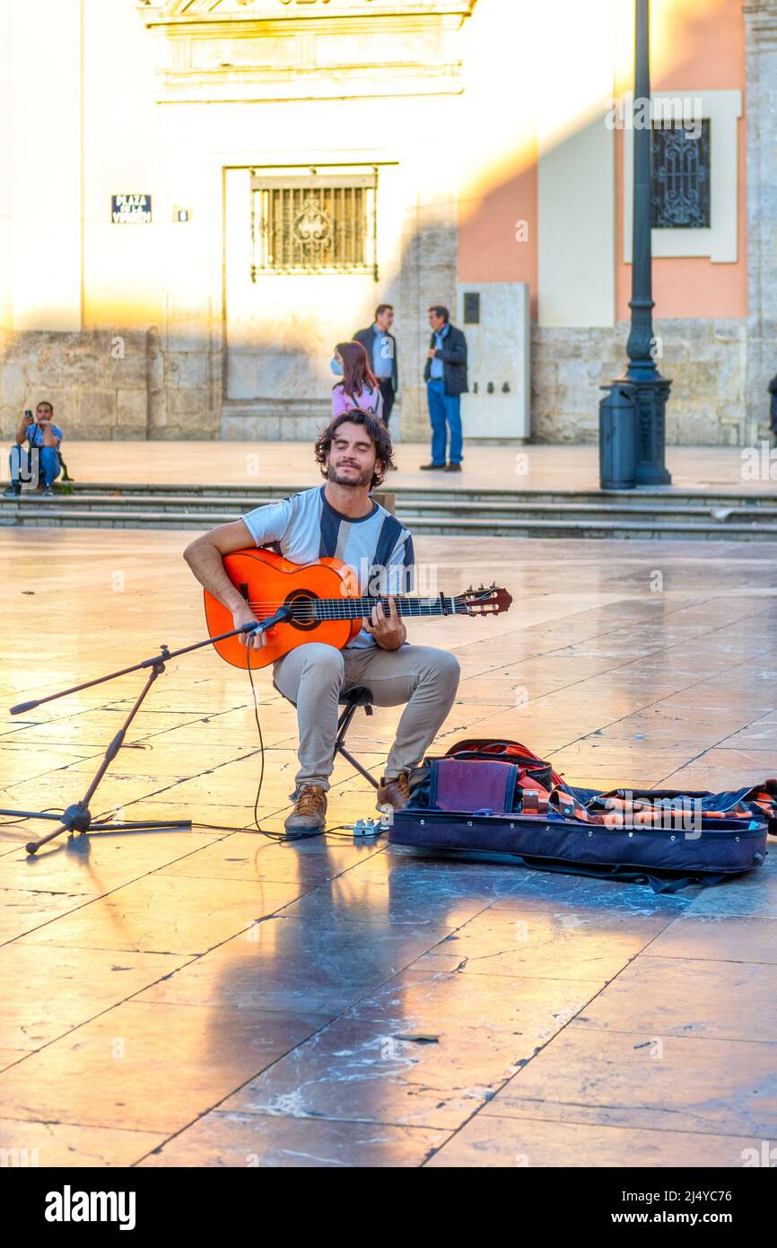 Young man busking with an acoustic guitar in the old town. This area is a major tourist attraction. Valencia city is the capital of the Spanish provin Stock Photo