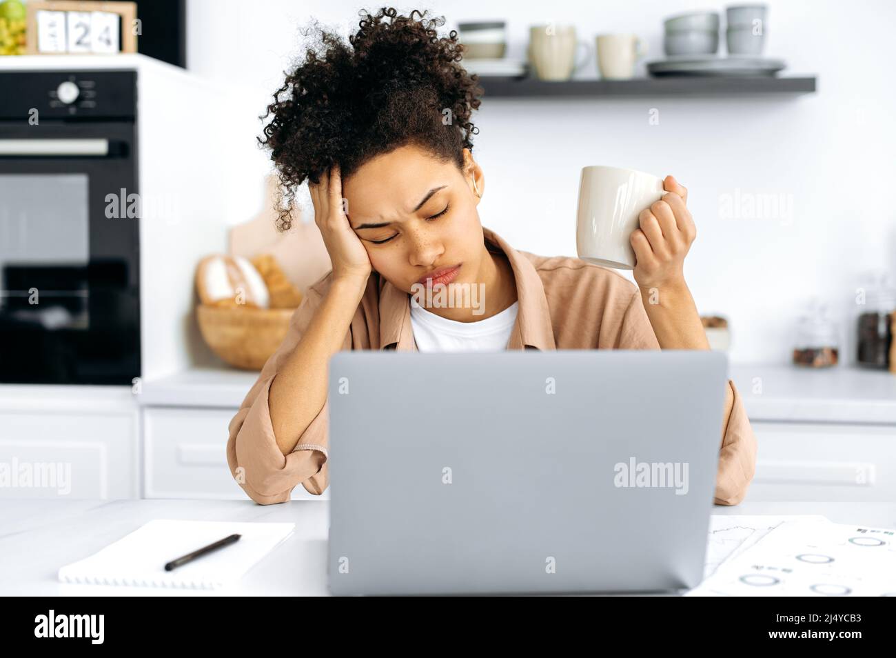Exhausted african american girl, female freelancer or student, working remotely from home, tired of boring online work, suffering from chronic fatigue, overwork, falls asleep at workplace, closed eyes Stock Photo