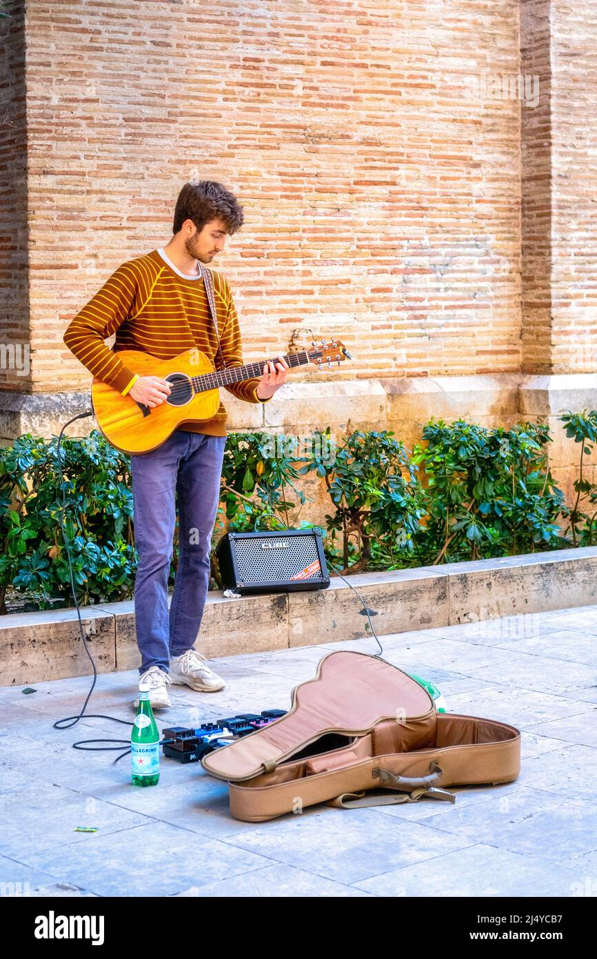 Young man playing guitar in the old town. This area is a major tourist attraction. Valencia City is the capital of the Spanish province of the same name Stock Photo