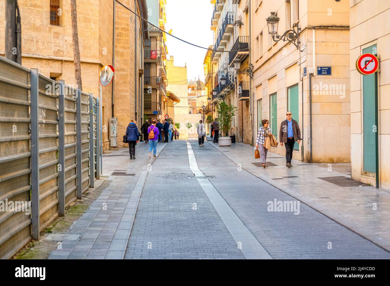 Narrow colonial-style street in the old town district. People go their daily routines in the area. This area is a major tourist attraction. Valencia c Stock Photo