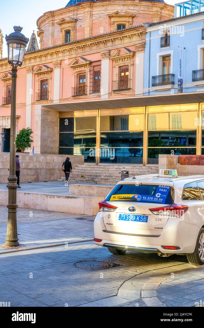 The rear part of a taxi is seen by the The Basilica del Virgen de los Desamparados in the old town. Valencia city is the capital of the Spanish provin Stock Photo