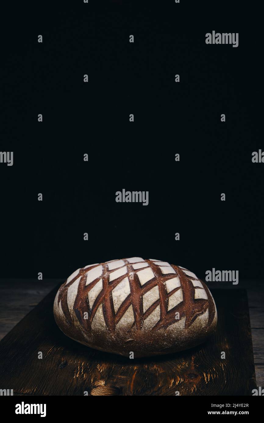 Loaf black rye bread sprinkled with flour on rustic wooden dark ...