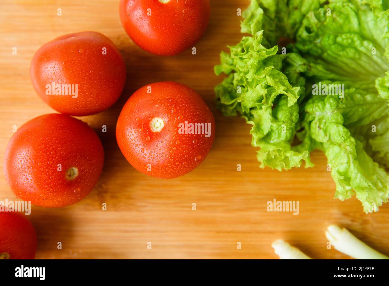 Fresh vegetables for salad lie on a wooden table with a cutting board. Top view. Close-up. Stock Photo