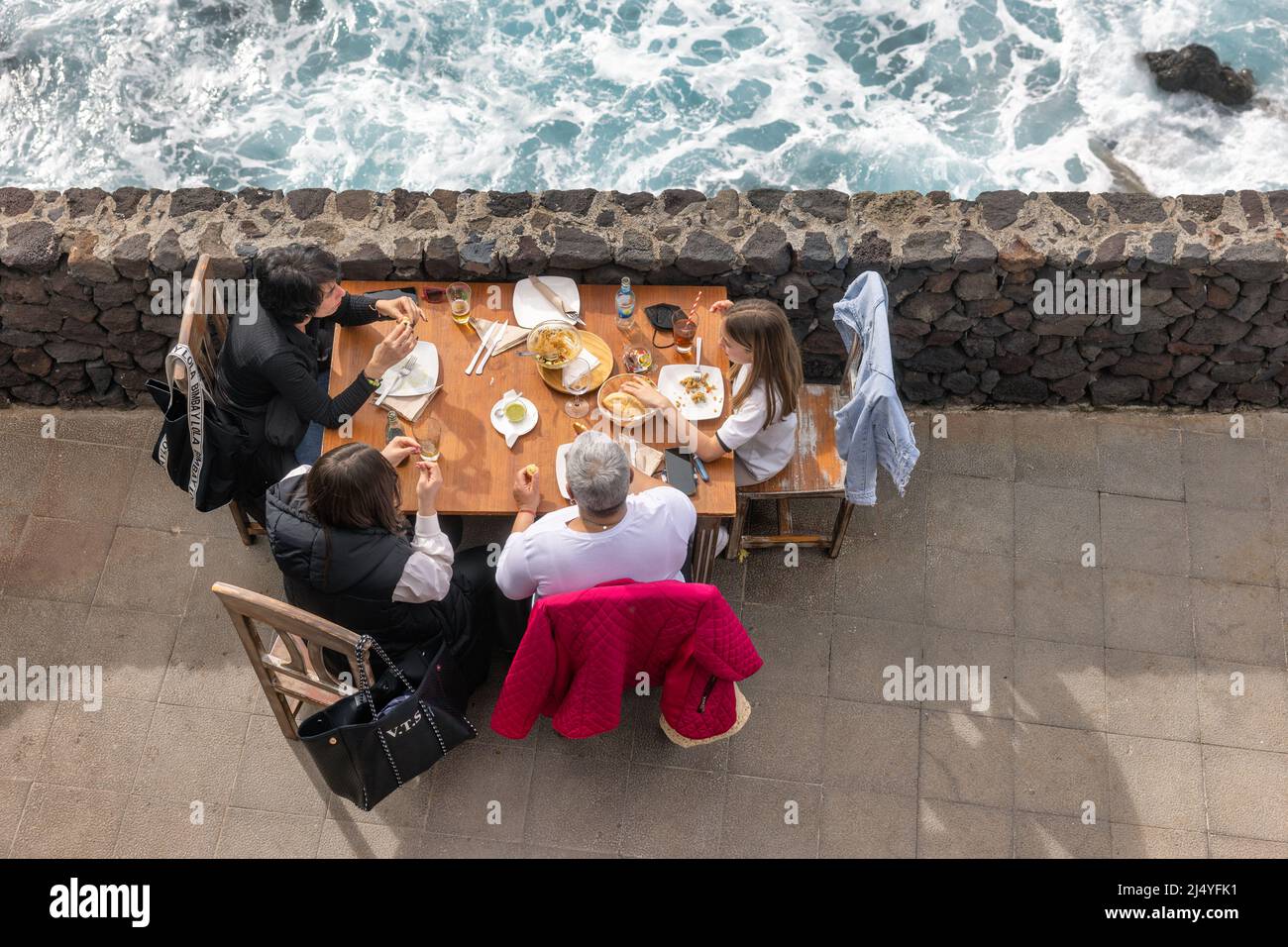 La Palma Island Spain - March 05, 2022: Top view family having lunch outside on a terrace besides the sea Stock Photo
