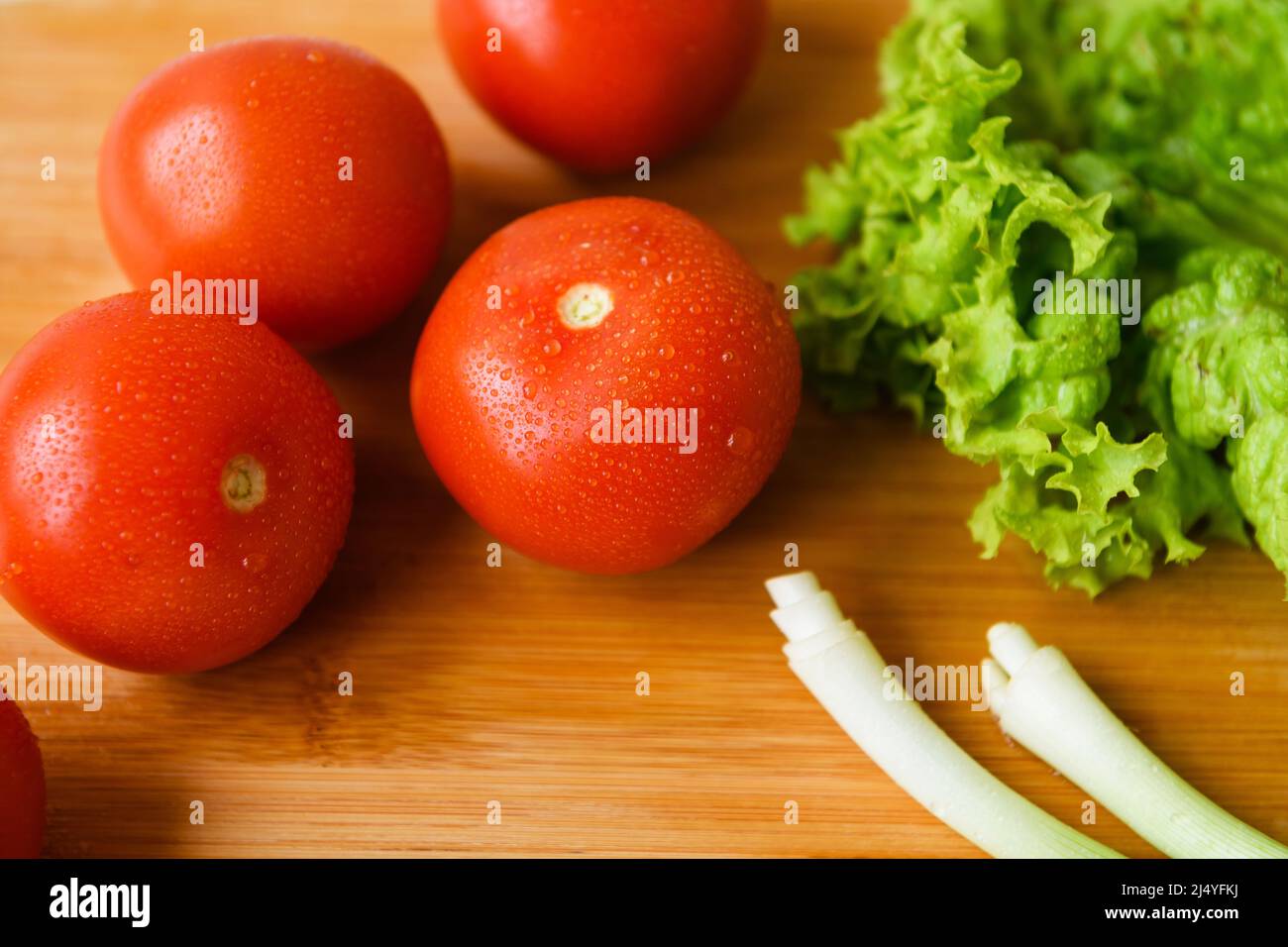 Fresh vegetables for salad lie on a wooden table with a cutting board. Top view. Stock Photo