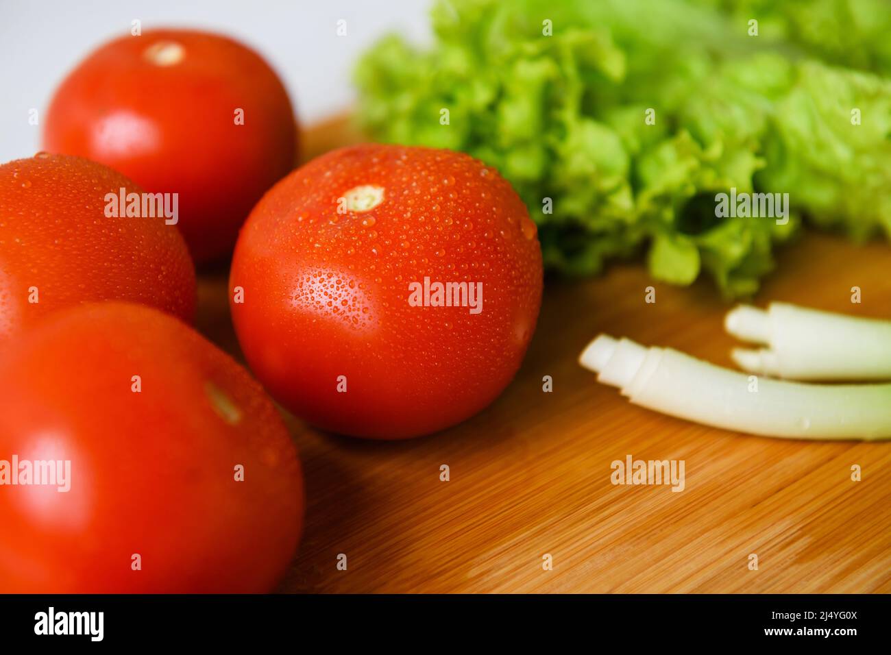 Fresh vegetables for salad lie on a wooden table with a cutting board. Close-up. Stock Photo