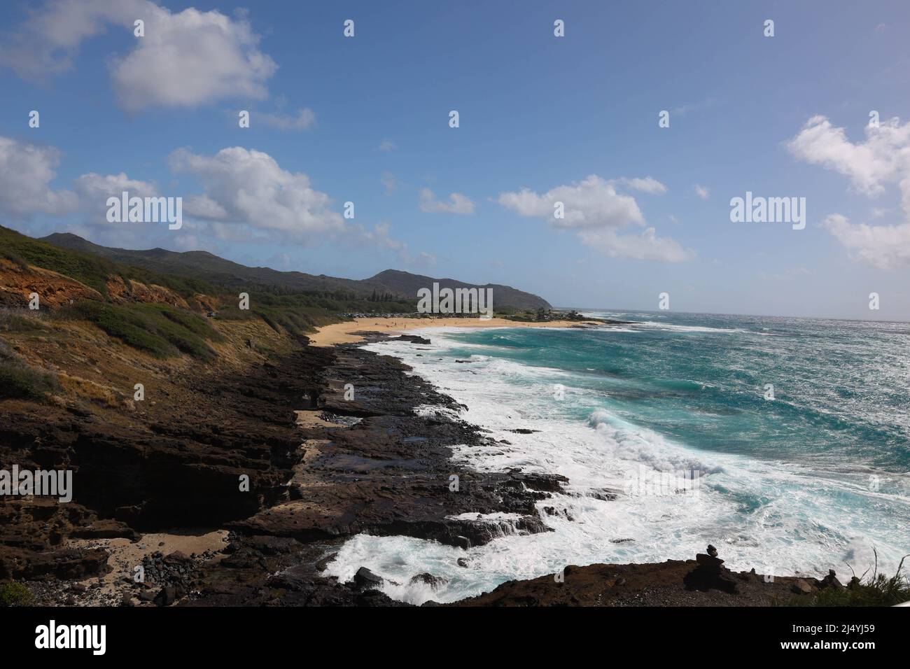 Sweeping beach scene with white waves.cliffs and blue sky Stock Photo