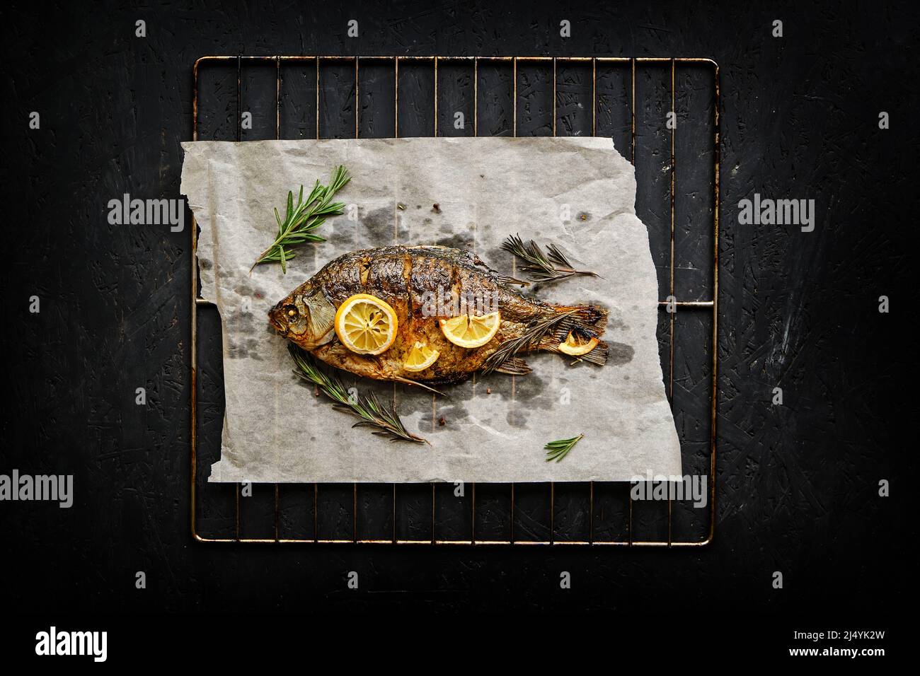 Baked fish cooked on parchment paper with spices, lemon and rosemary