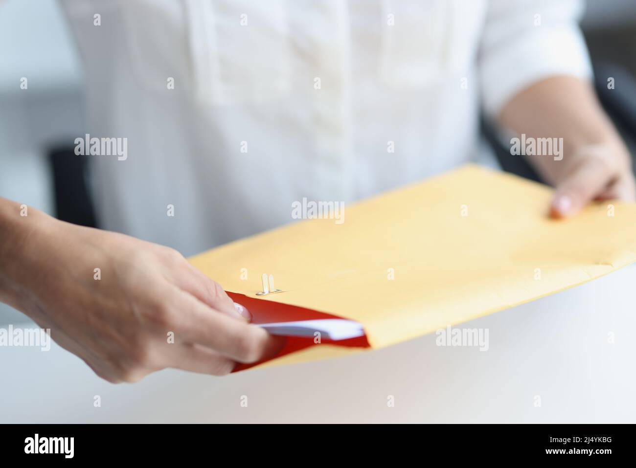 Woman client reads news in paper envelope at home desk Stock Photo