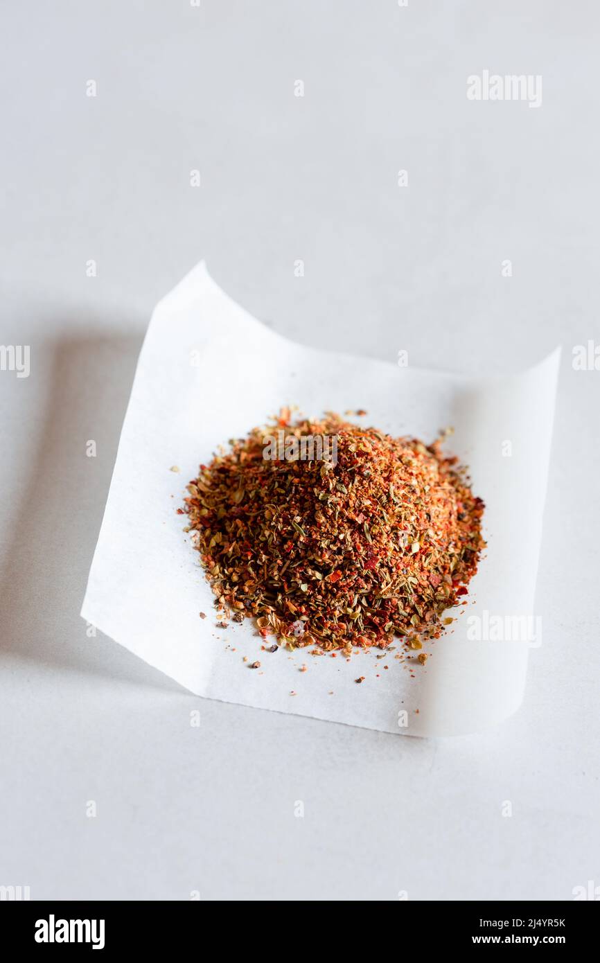 Chilli flakes and herbs on paper Stock Photo