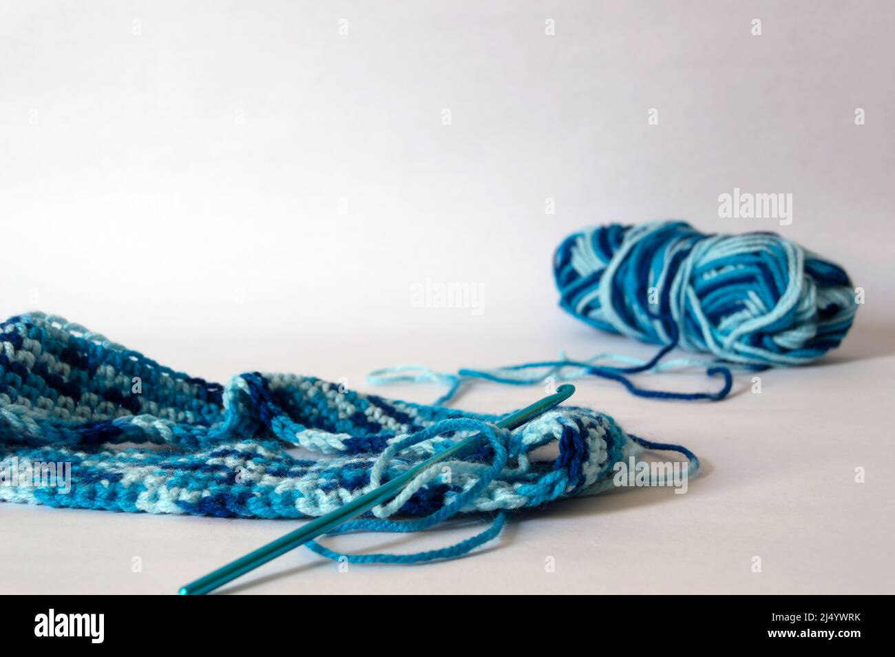 Work being made with crochet hook and blue gradient thread on white ...