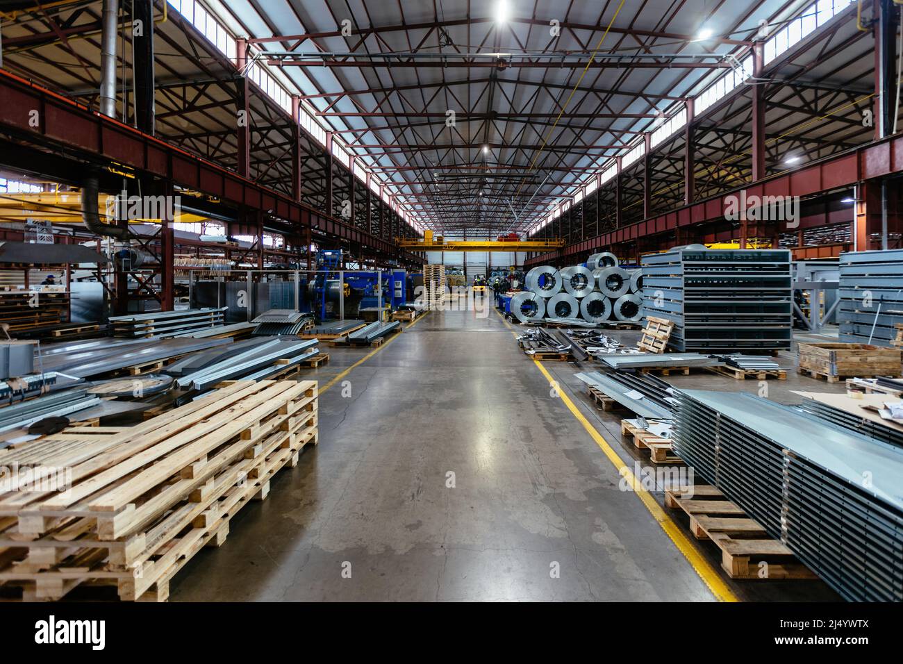Metalworking factory production line. Rolls of steel and metal profiled parts in workshop. Stock Photo