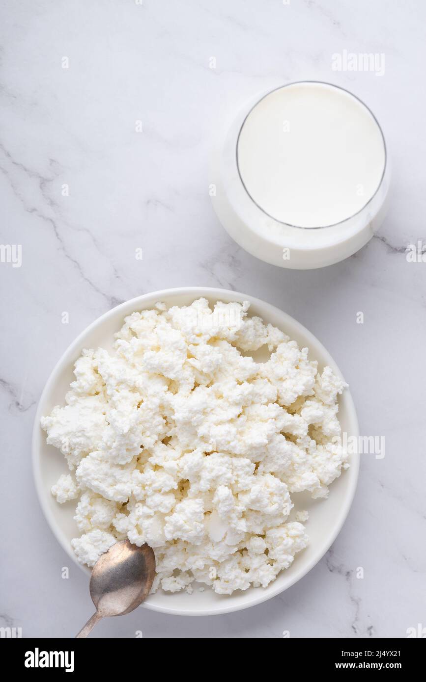 Bowl with fresh cottage cheese and milk on table. Space for text Stock