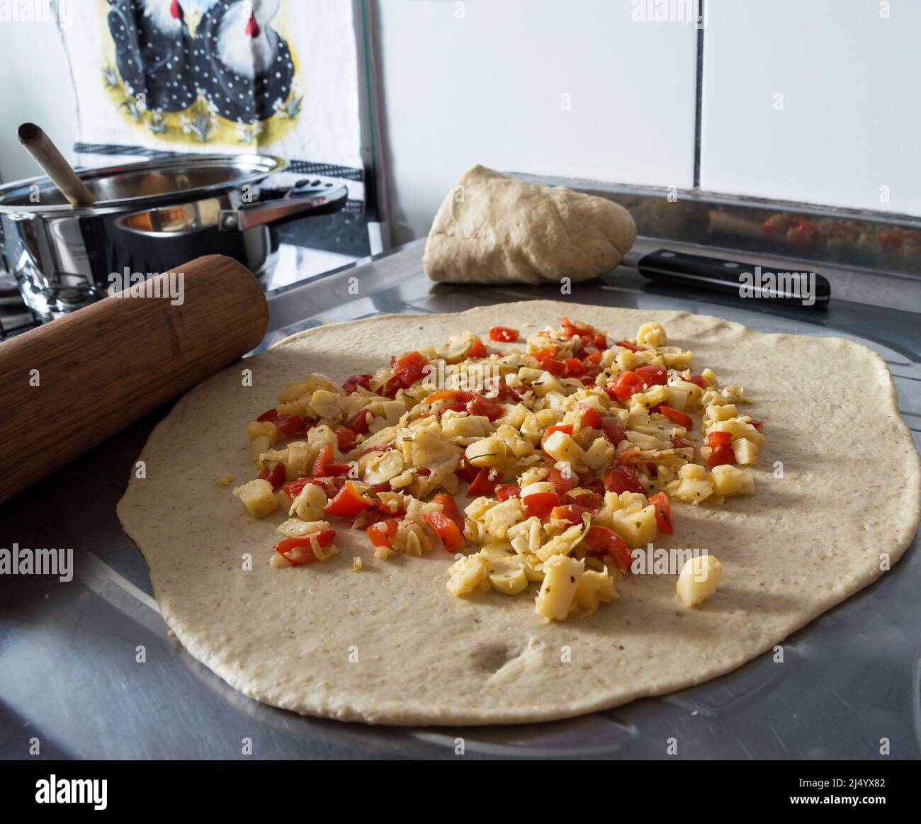 Uncooked pizza dough on a stainless steel countertop with hearts of