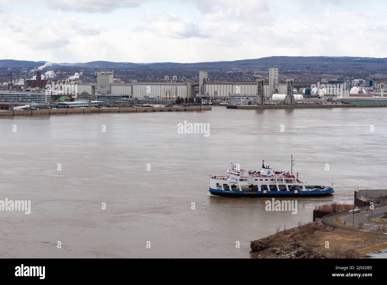 The ferry between Quebec and Levis crossing the St Lawrence river with the harbor of Quebec and these grain elevator in background Stock Photo