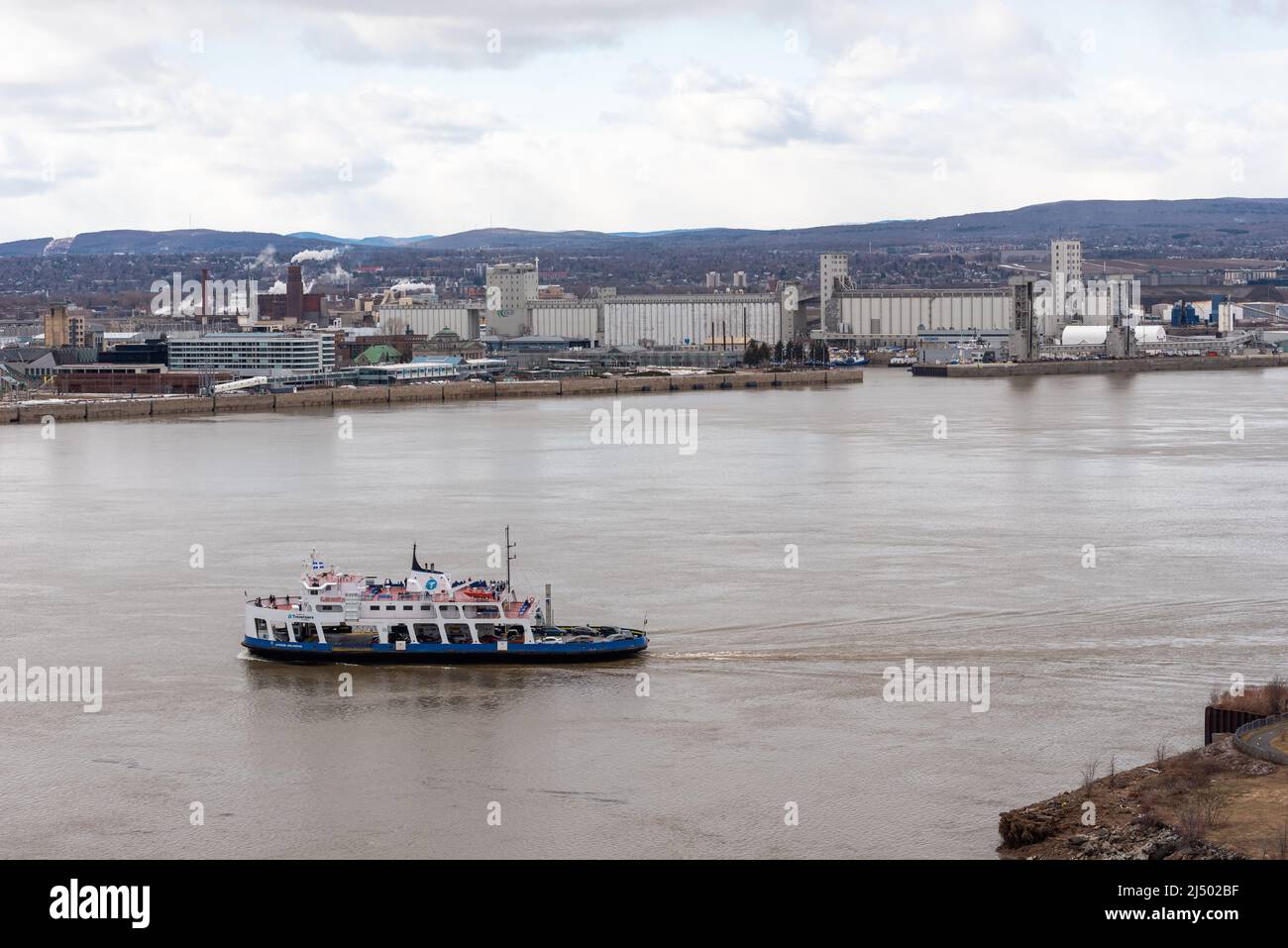 The ferry between Quebec and Levis crossing the St Lawrence river with the harbor of Quebec and these grain elevator in background Stock Photo