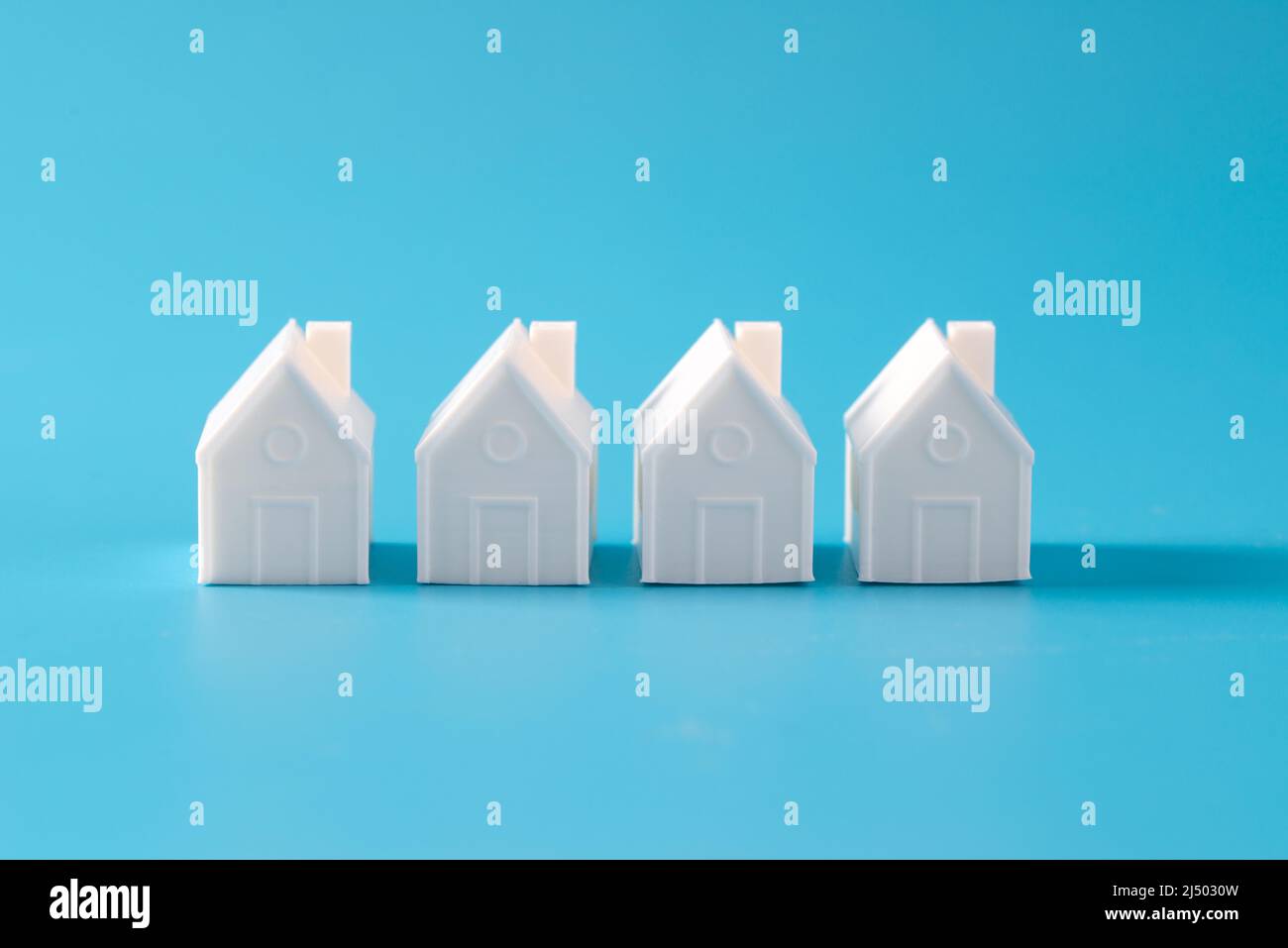 Miniature 3D printed model house on blue background Stock Photo