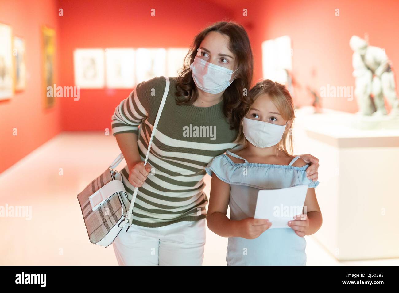 Mother and daughter in masks with guide enjoying expositions in museum ...