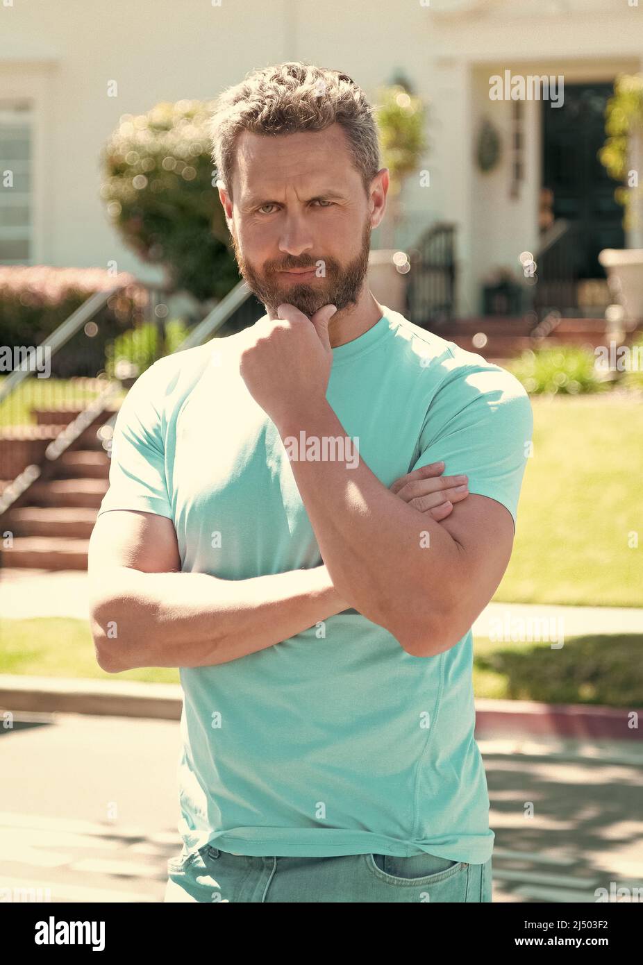 serious charismatic unshaven man touch his beard, male charisma Stock Photo