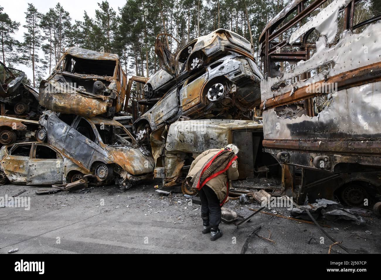 A Ukrainian woman looks at cars destroyed during the ongoing Russian invasion of Ukraine, at a junkyard in Irpin, Ukraine on Monday, April 18 2022. Russian troops entered Ukrainian territory resulting in fighting and destruction in the country, a huge flow of refugees, and multiple sanctions against Russia. Photo by Vladyslav Musiienko/UPI Credit: UPI/Alamy Live News Stock Photo