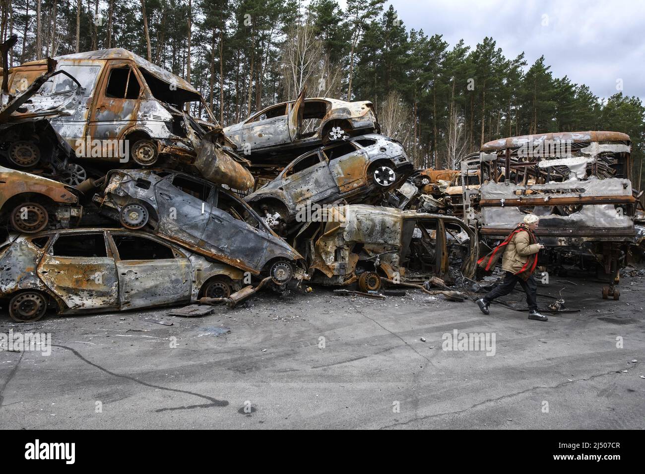 A Ukrainian woman walks beside cars destroyed during the ongoing Russian invasion of Ukraine, at a junkyard in Irpin, Ukraine on Monday, April 18 2022. Russian troops entered Ukrainian territory resulting in fighting and destruction in the country, a huge flow of refugees, and multiple sanctions against Russia. Photo by Vladyslav Musiienko/UPI Credit: UPI/Alamy Live News Stock Photo