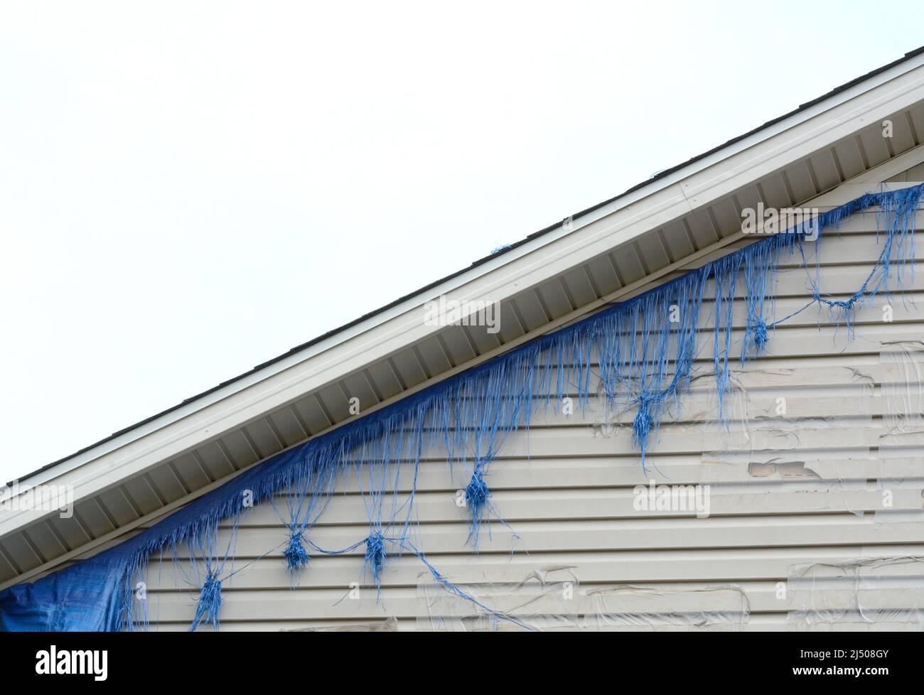 Frayed tarp from wind that was covering holes in walls of home cause by hail Stock Photo